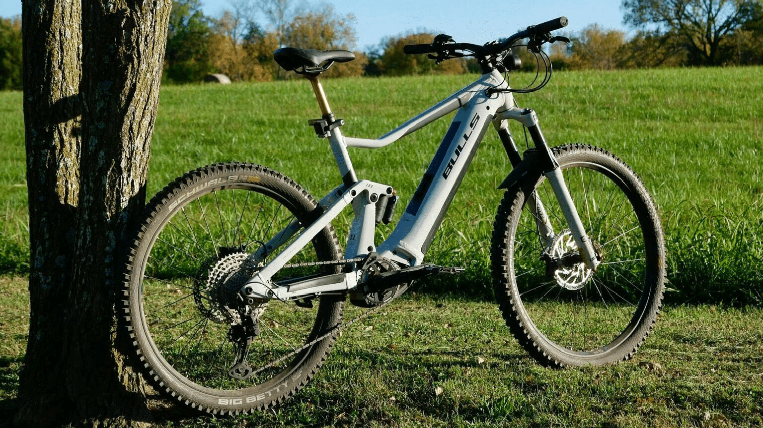Full Charge Cycles – Copperhead EVO Mountain bike, Full Charge Cycles - Copperhead EVO, leaning against a tree in a natural outdoor setting.