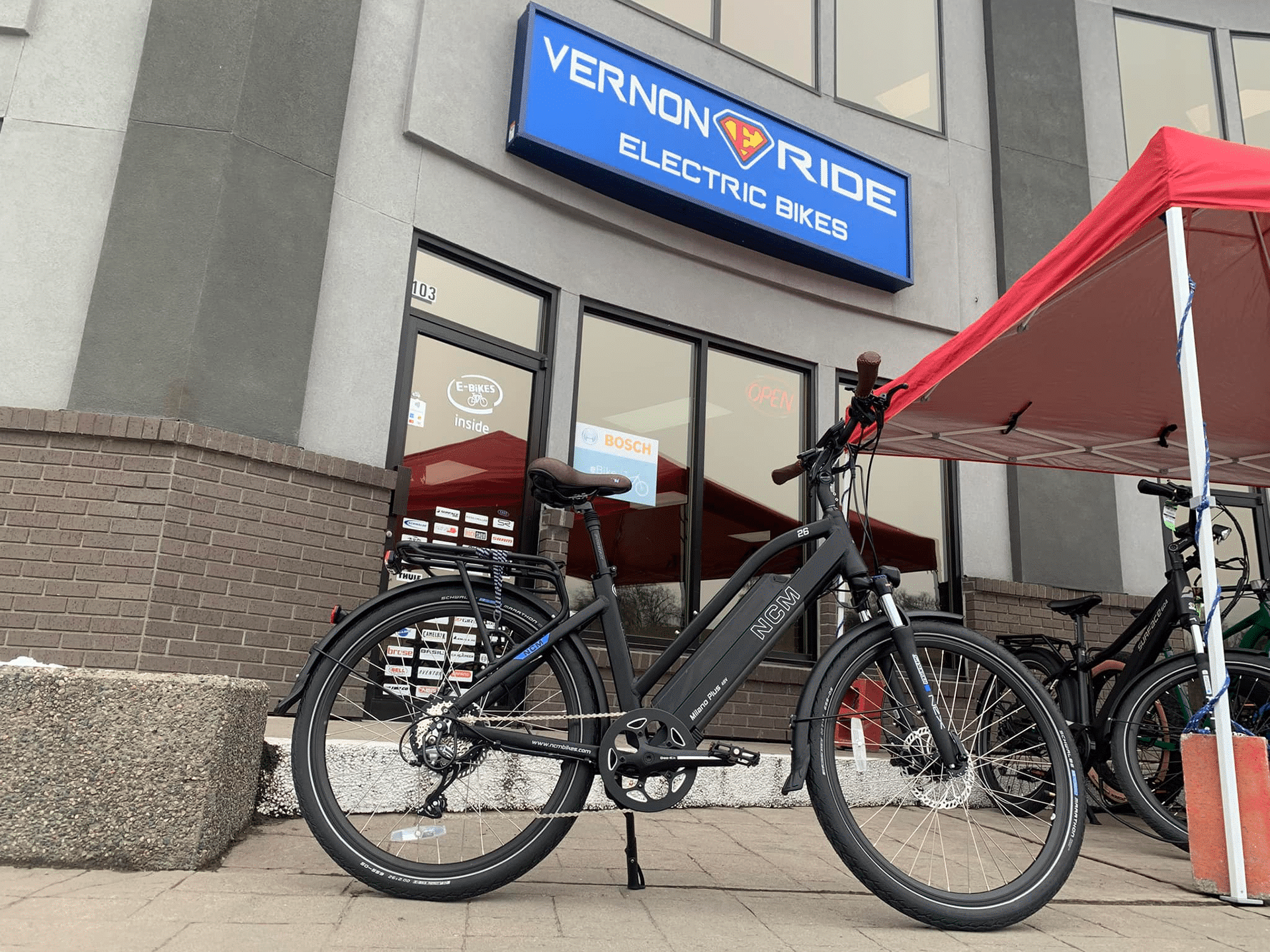 Bicycle parked outside Full Charge Cycles store in Vernon, showcasing the shop's entrance and surrounding area.