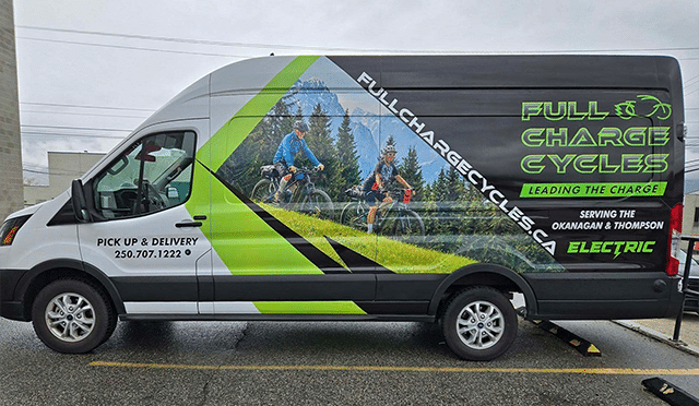 A van displaying a full charge cycle logo, indicating its electric vehicle status and commitment to sustainability.